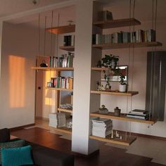 a living room filled with furniture and bookshelves next to a wall mounted book shelf