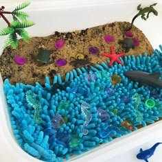 an ocean scene made out of blue sponges and plastic sea animals on the sand