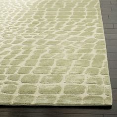 a green rug with an animal print pattern on the top and bottom, sitting on a hardwood floor