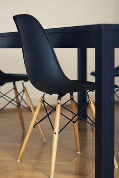 a black table with four chairs and a wooden floor in front of it on top of a hard wood floor