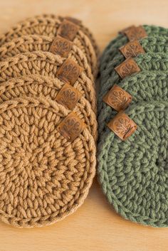 three crocheted hats with wooden buttons on them sitting on top of a table