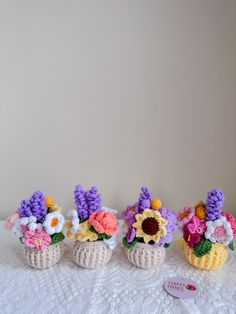 three crocheted vases with flowers in them sitting on a white tablecloth