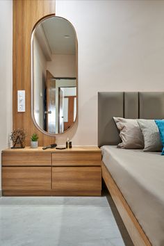 a bed sitting next to a wooden dresser under a large mirror on top of a wall