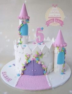 a white cake with pink and blue frosting on it's top is decorated like a princess castle