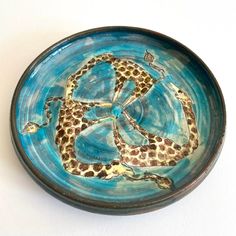 a ceramic bowl with an octopus and giraffe design on the bottom, sitting on a white surface