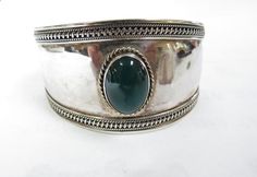 The cuff bracelet is not marked but has been tested to be solid sterling silver. It weighs 24.7 grams. It will fit up to a 7 1/2" wrist and is somewhat adjustable. bezel set in the center is a green oval natural onyx. It measures 17 mm x 13 mm. The bracelet on the inside could use a silver polish. It is in nice condition. Silver Oval Cuff Bracelet, Formal Silver Oval Cuff Bracelet, Silver Oval Cuff Bracelet With Polished Finish, Adjustable Oval Cuff Bracelet, Oval Cuff Bracelet With Polished Finish, Silver Polish, Green Oval, Sterling Silver Cuff Bracelet, Yellow Gold Pendants