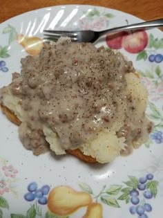 a plate topped with mashed potatoes covered in gravy next to a fork