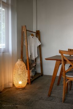 a table and chair in a room with a lamp on the floor next to it