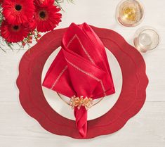 a place setting with red napkins and flowers