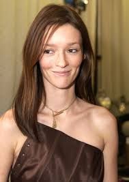 a woman in a brown dress posing for the camera with her hand on her hip