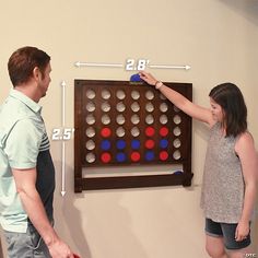 a man and woman standing next to each other in front of a giant game board