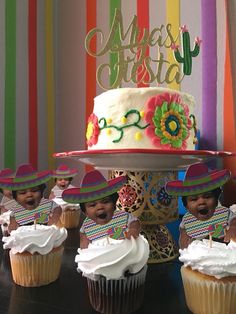 some cupcakes are sitting in front of a cake with the word fiesta on it