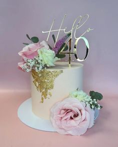 a white cake with pink flowers and the number forty on top is sitting on a plate