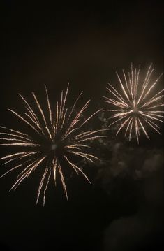 fireworks are lit up in the night sky with dark clouds and black skies behind them