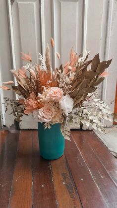 a blue vase filled with lots of flowers on top of a wooden table next to a white door