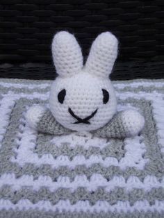 a white crocheted stuffed animal laying on top of a blanket in the shape of a bunny