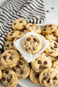 a plate full of chocolate chip cookies on top of a striped cloth with a napkin