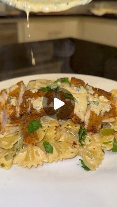 a white plate topped with pasta and meat covered in sauce on top of a counter