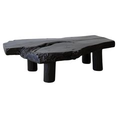 a table made out of black wood with two large pieces of rock on it's legs