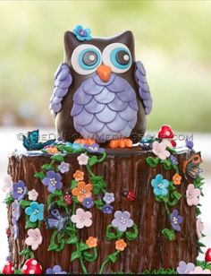 an owl figurine sitting on top of a tree stump decorated with flowers and butterflies