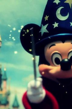 mickey mouse in front of a castle with stars on it's hat and holding a wand