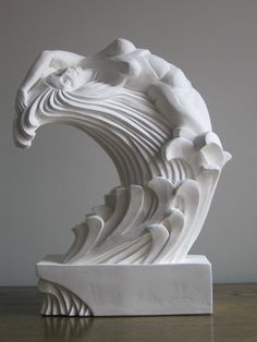 a white sculpture sitting on top of a wooden table next to a wall and floor