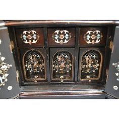 an ornately decorated wooden cabinet with metal decorations on the front and sides, in black