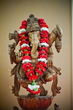 an elephant statue with red and white flowers on it