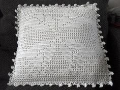 a white crocheted pillow sitting on top of a black couch