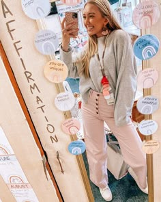 a woman taking a selfie in front of a wall covered with stickers and magnets