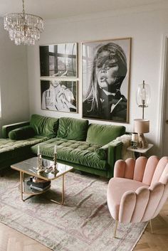 a living room with green couches and pictures on the wall above them, as well as a chandelier