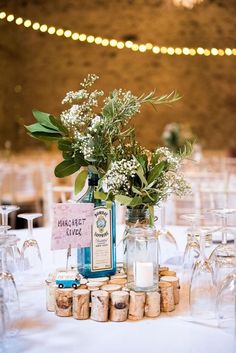 a table topped with wine glasses and vases filled with flowers on top of it