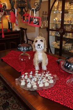 a dog is sitting on top of a table with cupcakes and cakes in front of it