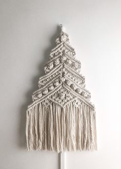 a white christmas tree hanging on the wall with tassels and beads around it