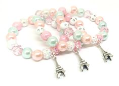 a bracelet with pink, white and green beads on it's ends that have the eiffel tower charms attached to them