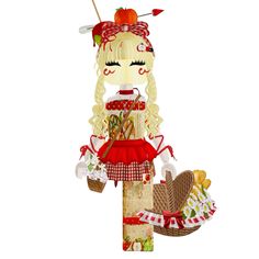 the doll is wearing a red dress and holding a basket with food on it's head