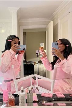 two women in pink pajamas taking pictures with their cell phones