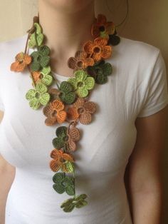 a woman wearing a crocheted necklace with flowers and leaves hanging from it's neck