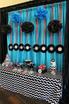 a table topped with cake and cupcakes next to a wall covered in blue curtains