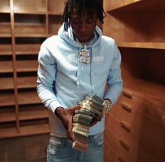 a man in a blue hoodie holding stacks of books