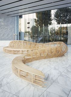 two wooden benches sitting on top of a white marble floor next to a tall building