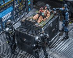 some action figures are sitting on top of a crate in the middle of a sci - fi setting