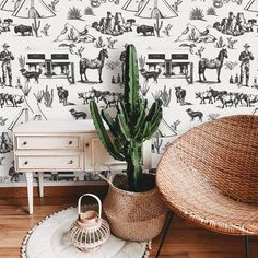 a cactus in a wicker basket next to a white dresser and wallpaper with horses on it