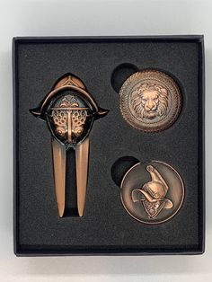 an open box with three different types of brooches and two other items in it