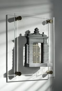 a mirror that is on the wall with a building in it and some light coming through