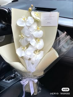 a bouquet of white orchids wrapped in cellophane and tied to a car steering wheel