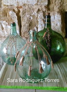 three green vases sitting next to each other on top of a table with stone wall behind them