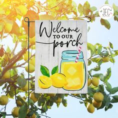 a welcome sign hanging from the side of a tree with lemons and a mason jar