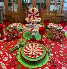 a table set for christmas with candy canes on the plates and red napkins