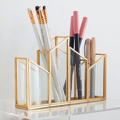 a pen holder with pens and pencils in it on top of a glass table